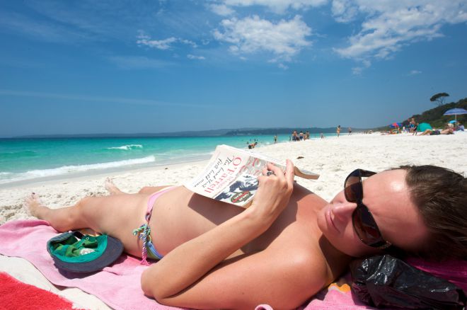 Moteris su knyga paplūdimyje